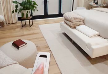 Close-up of Somfy motorized window shades operated by a remote control, showing seamless integration with modern bedroom decor.