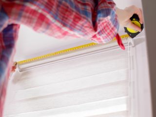 A man takes a mesure for blinds installation in Santa Monica